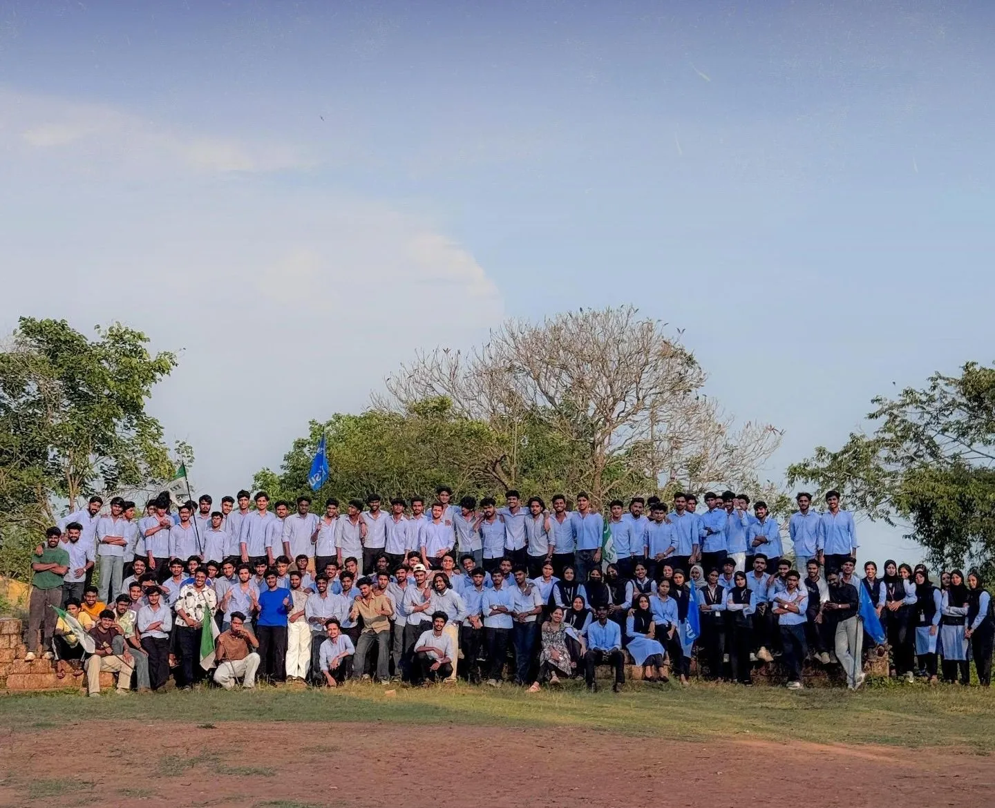 Over a hundred UDSF members at GEC Wayanad posing together on a hilltop with KSU and MSF flags
